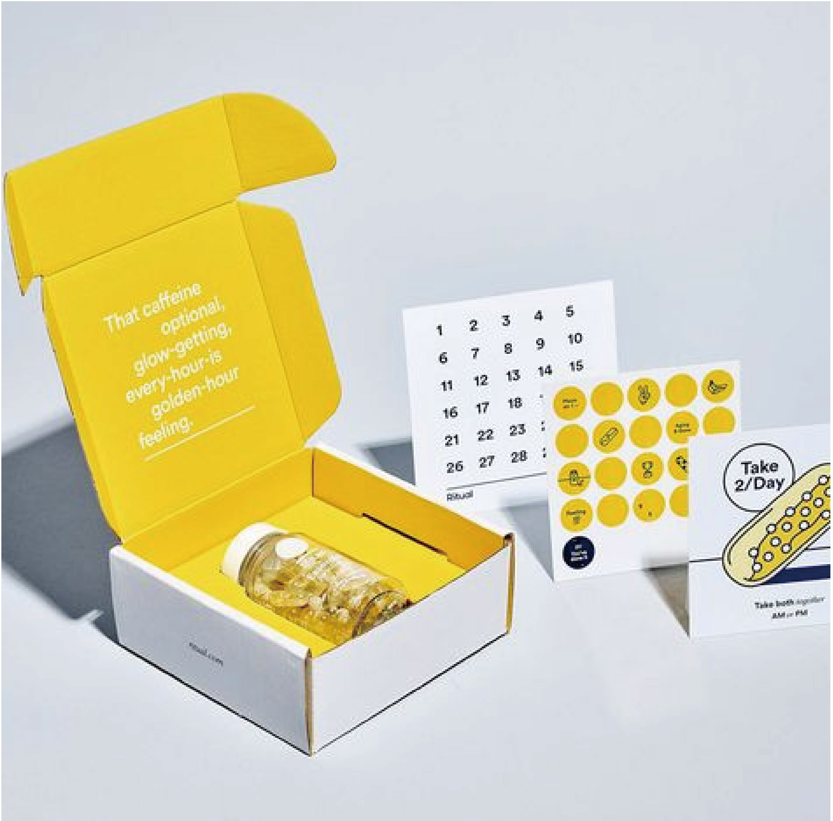 在白色的背景下，左邊擺放了一個打開的白色郵寄盒，盒內以黃色為主，擺放了一枝液體的化妝品，而右邊則擺放了3張宣傳紙品。