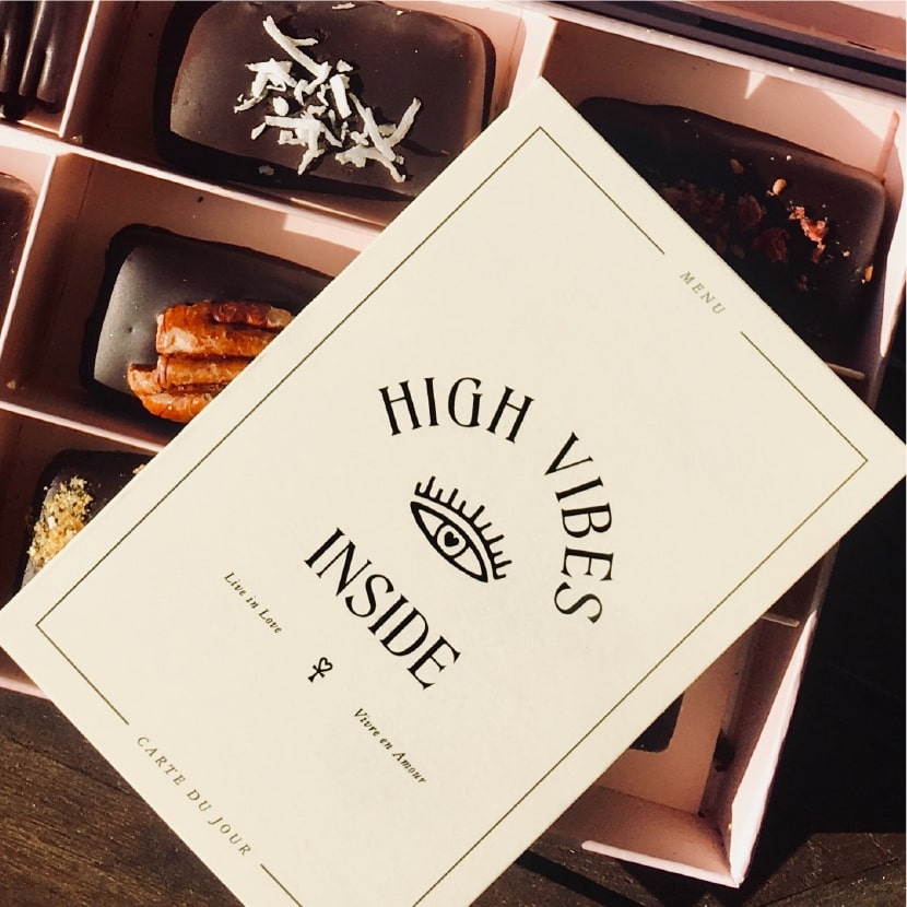 在朱古力的產品上方，擺放了一張印有"HIGH VIBES INSIDE" 字眼的品牌宣傳紙品。