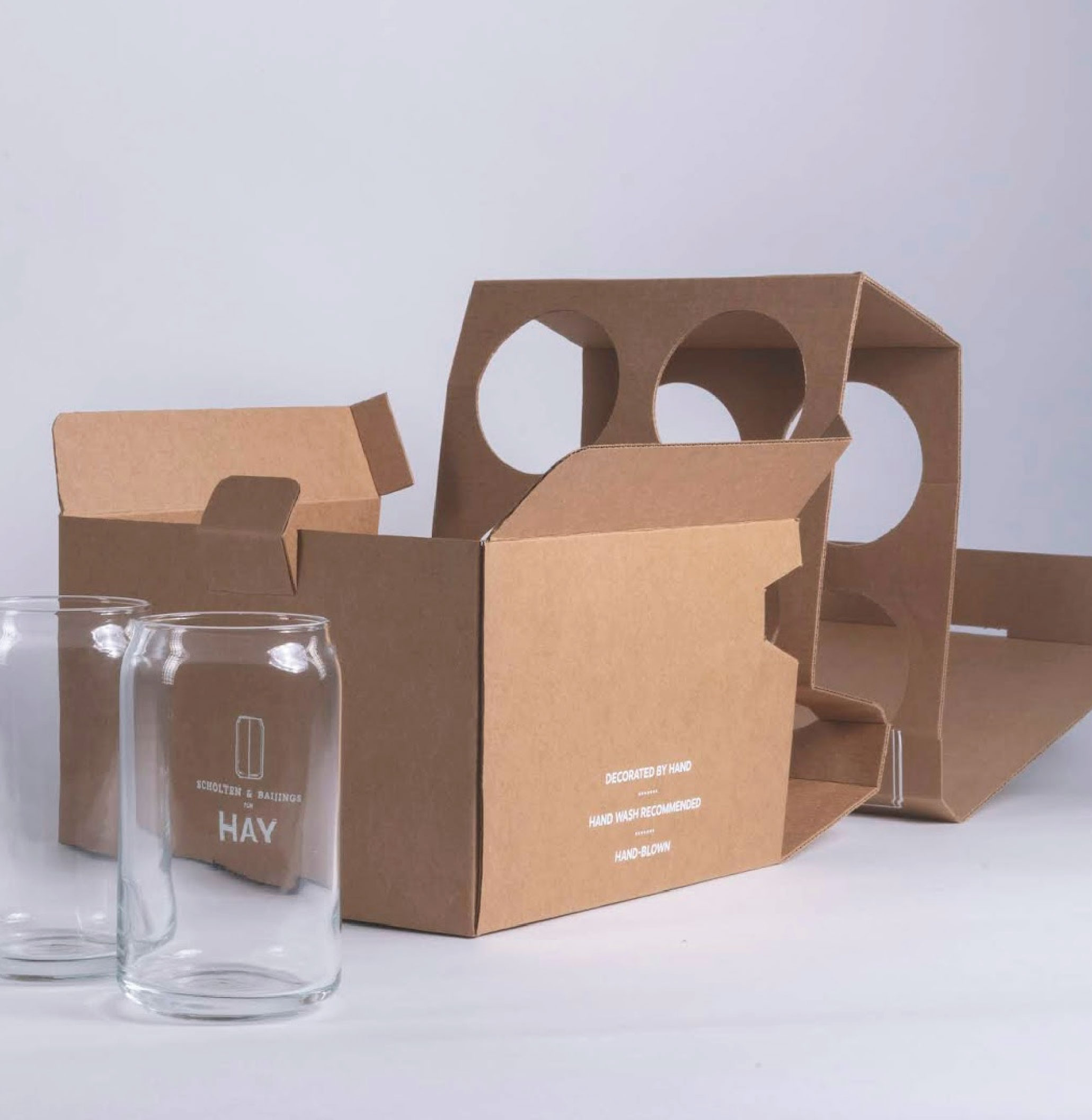 在灰色的背景下，擺放了一個牛皮紙盒加上內托，而盒外放了兩個玻璃杯。