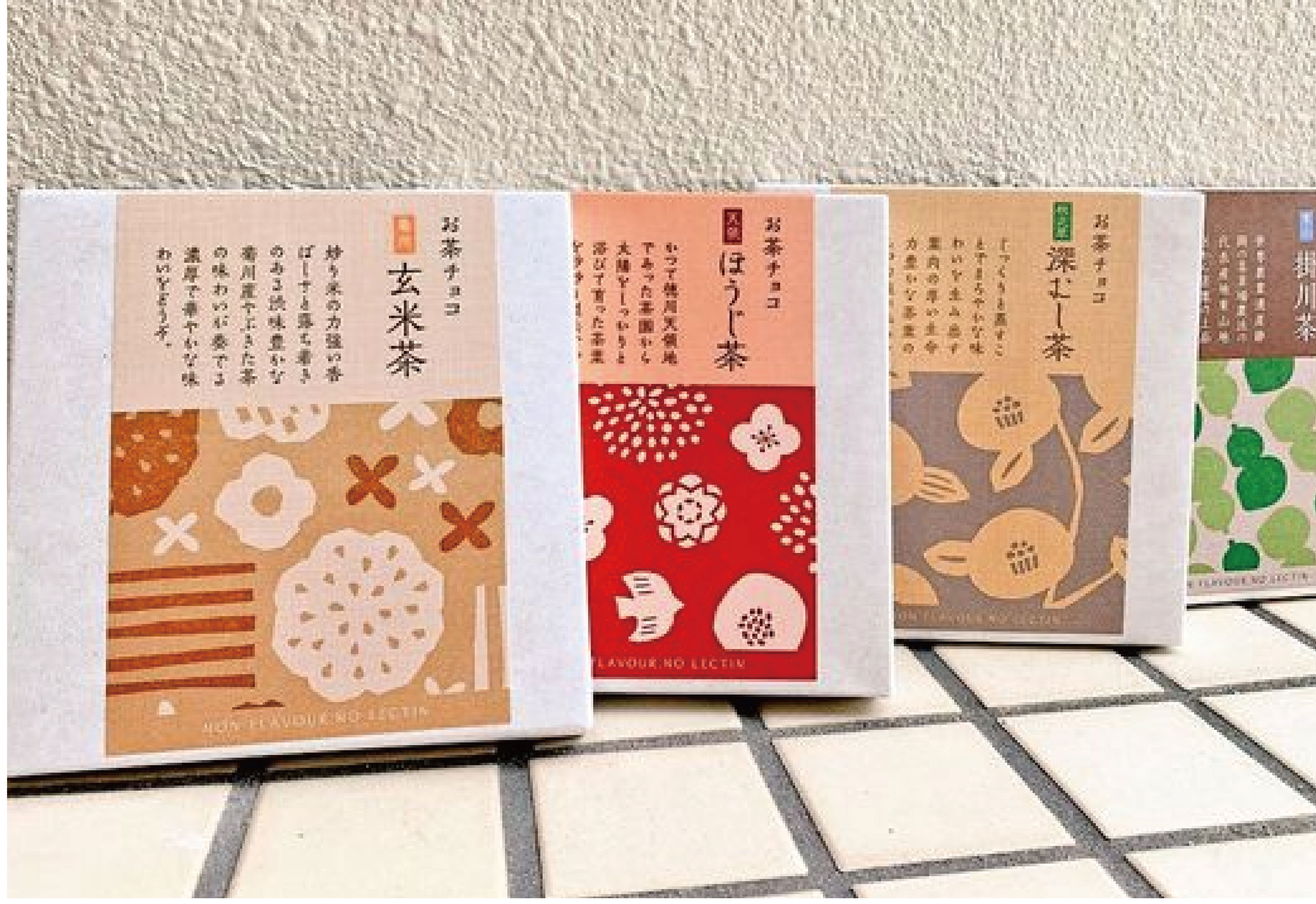 在灰色的背景下，擺放了四個不同顏色的彩色郵寄盒，盒上各印有不同茶葉種類的字眼。