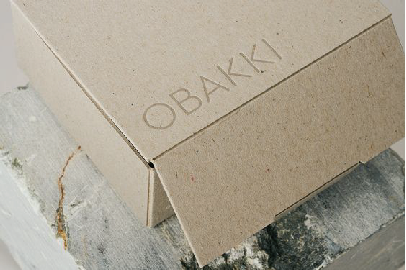 一塊石頭上擺放著一個以卡其色為主的紙盒。上面印有"OBAKKI"的字樣。