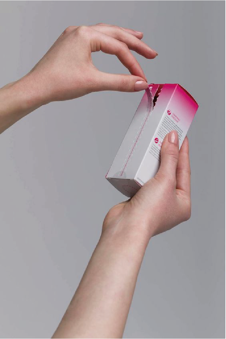一雙手在撕開一個白色為主，頂部有粉色漸變色的包裝盒。