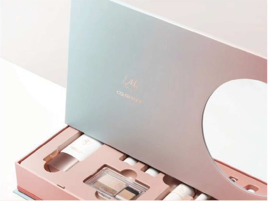 在白色的背景下，擺放了一個打開了的磁石書型硬盒，硬盒以粉紅和粉藍色的為主，盒內放置了多款不同的化妝品。
