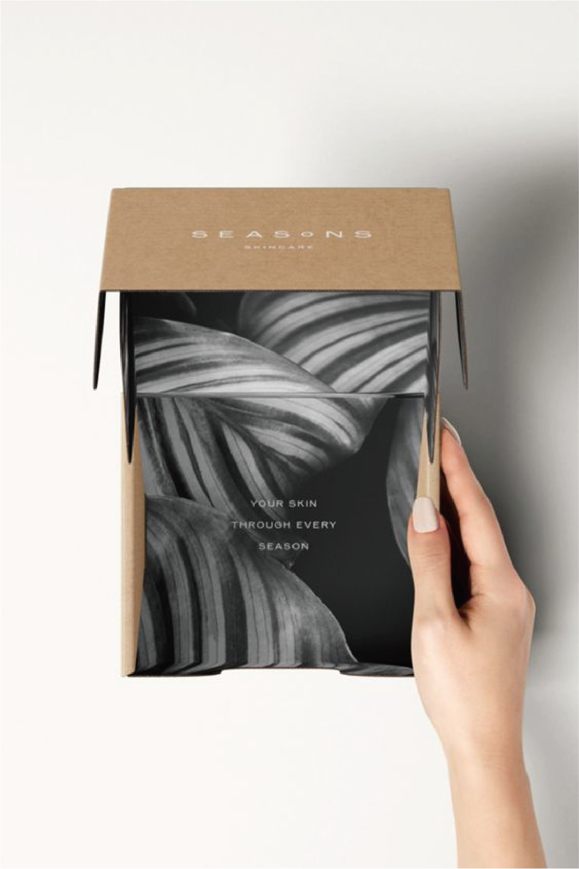 有隻手拿著一個啡色的盒，裡面印有很多黑白灰色的不規則間紋。