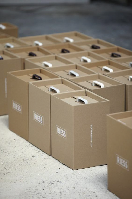 在地上放滿了手抽式的牛皮紙箱，手抽分別有黑色和白色，而紙箱上則以白色印上"RIESS"的商標。