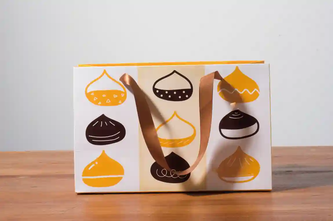 A mockup of a ribbon paper bag displayed on a gray background and wood grain tabletop