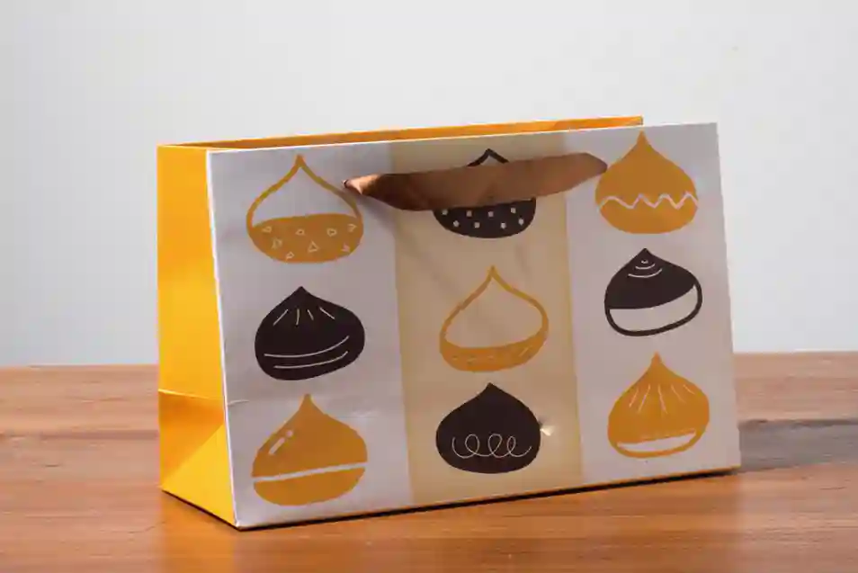 A mockup of a ribbon paper bag displayed on a gray background and wood grain tabletop