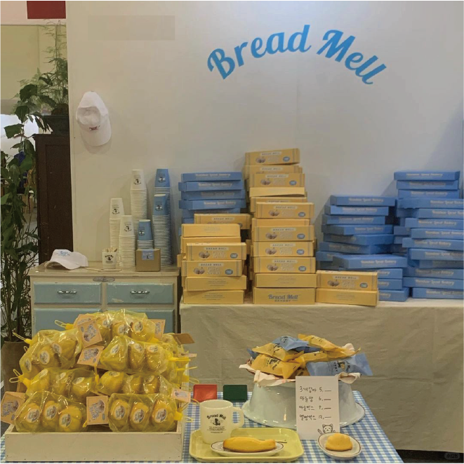 The bakery displays yellow and blue boxes and pastries, with 'Bread Mell' written on the back wall.