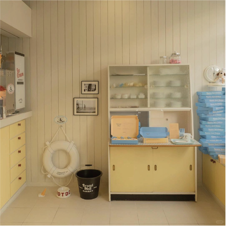 A cosy bakery corner with a vintage style cooler with blue bakery boxes and decorations on the top and next to it.