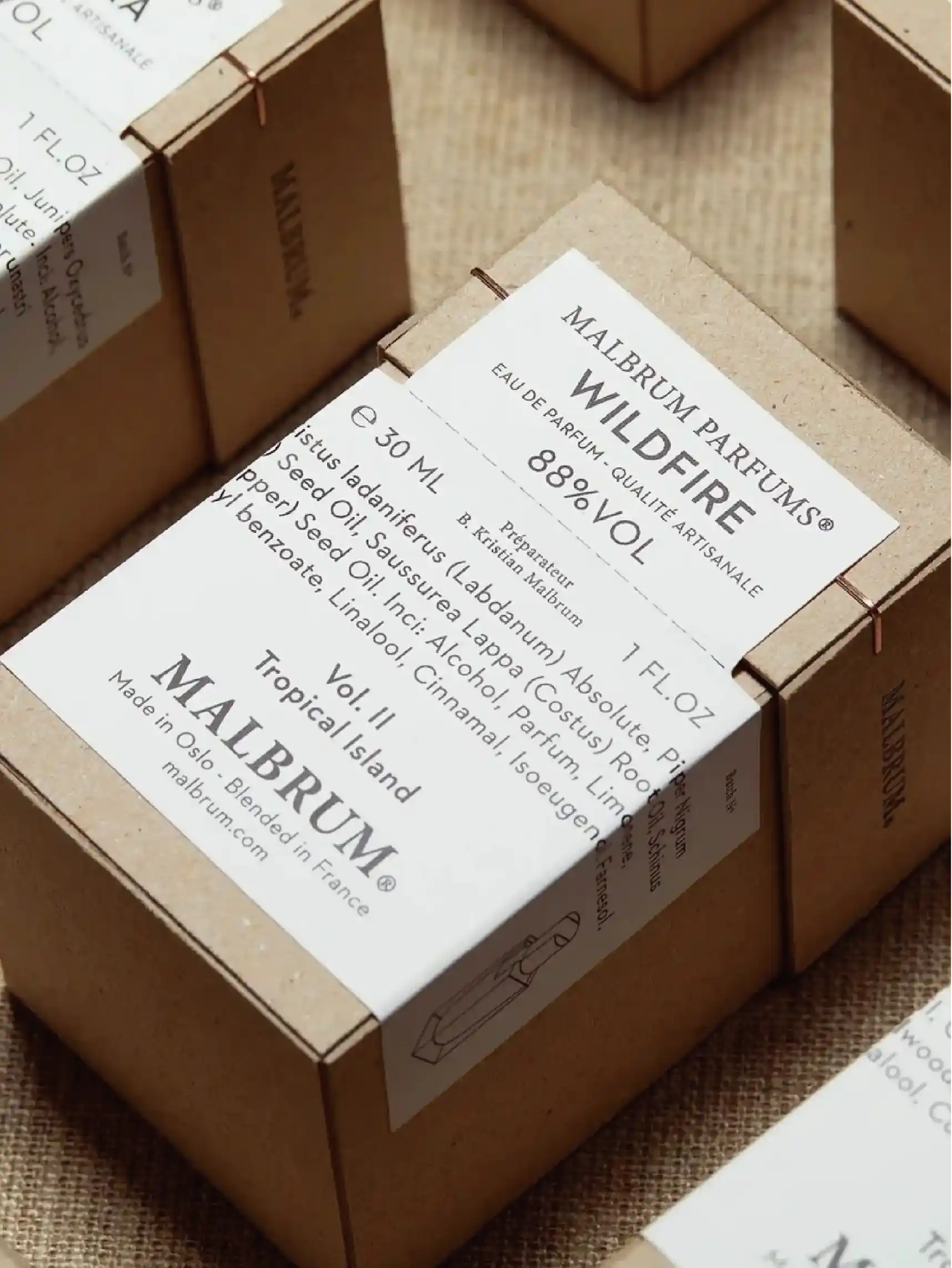 Displaying an open perfume box with a bottle of perfume inside, the box is printed with the brand name "MALBRUM PARFUMS" and the name of the perfume "WILDFIRE", as well as the details of the perfume.