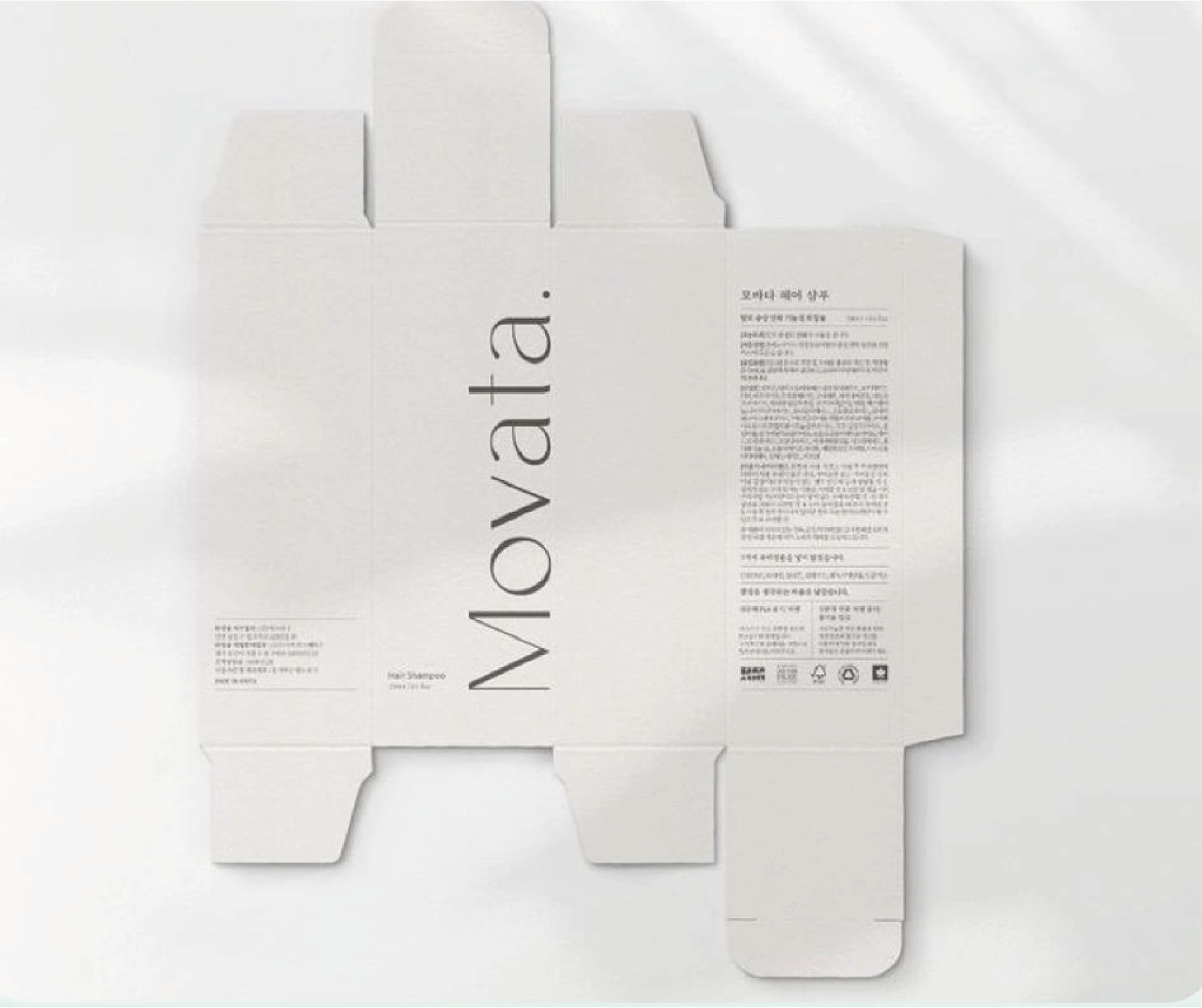 An unfolded cardboard package, white in colour, with the word "Movata" and some explanatory text in Korean.