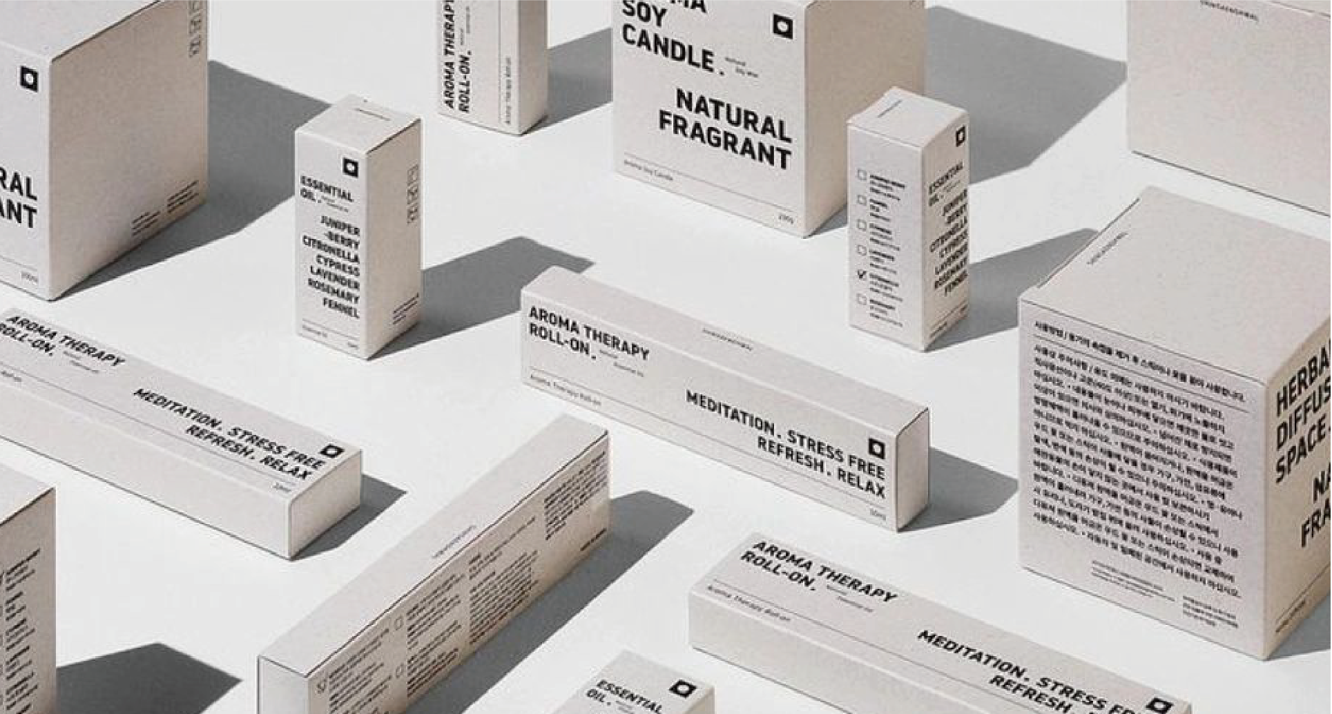White boxes of different sizes are scattered on a grey background, with black text describing the product information, such as "AROMA THERAPY", "SOY CANDLE", etc., giving a minimalist and modern feel.