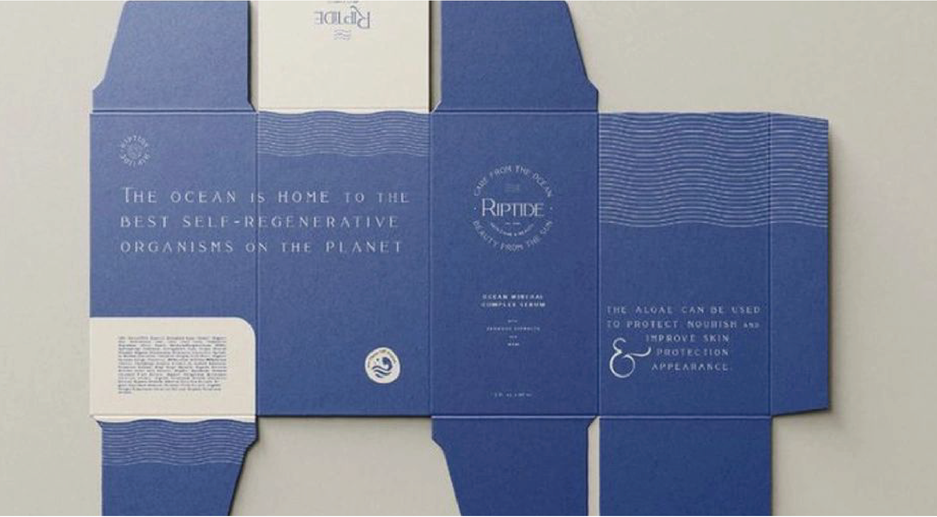 The unfolded dark blue box is printed with white text describing the product's ocean-related properties and is decorated with a wave pattern.