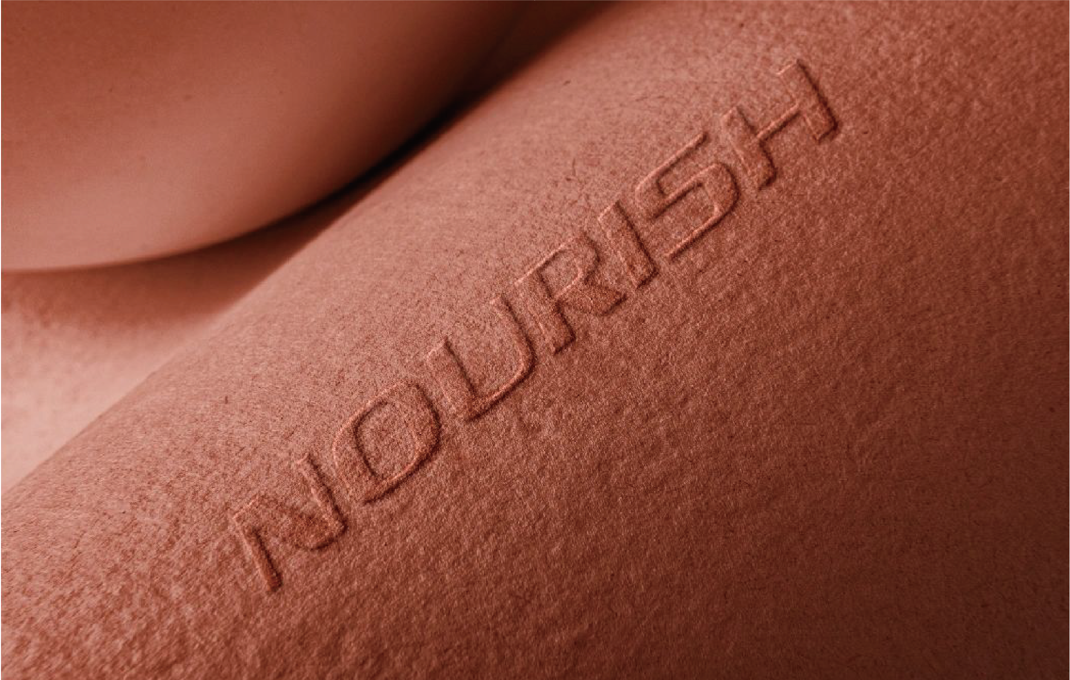 The image shows a warmly coloured box surface with the word "NOURISH" printed in stereoscopic form by means of a percussive overpressure.