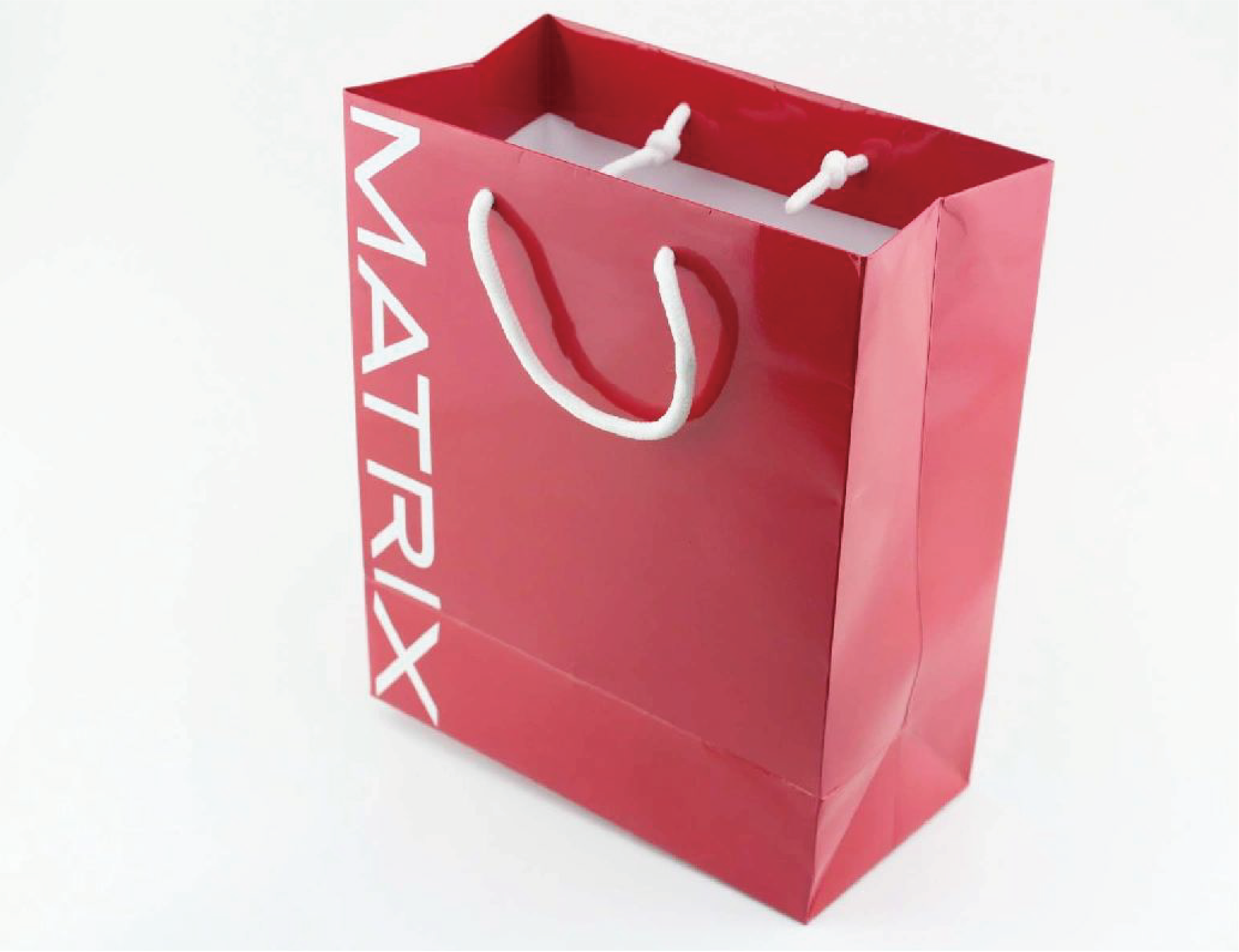 The image shows a bright red shopping bag with white letters spelling out 'MATRIX'. The bag has two white string handles.