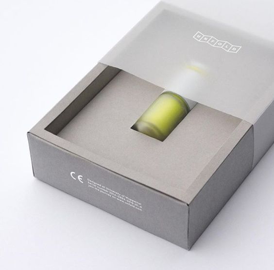 A simple grey cosmetic box with a transparent window to display the green bottle inside, combining aesthetics and functionality.