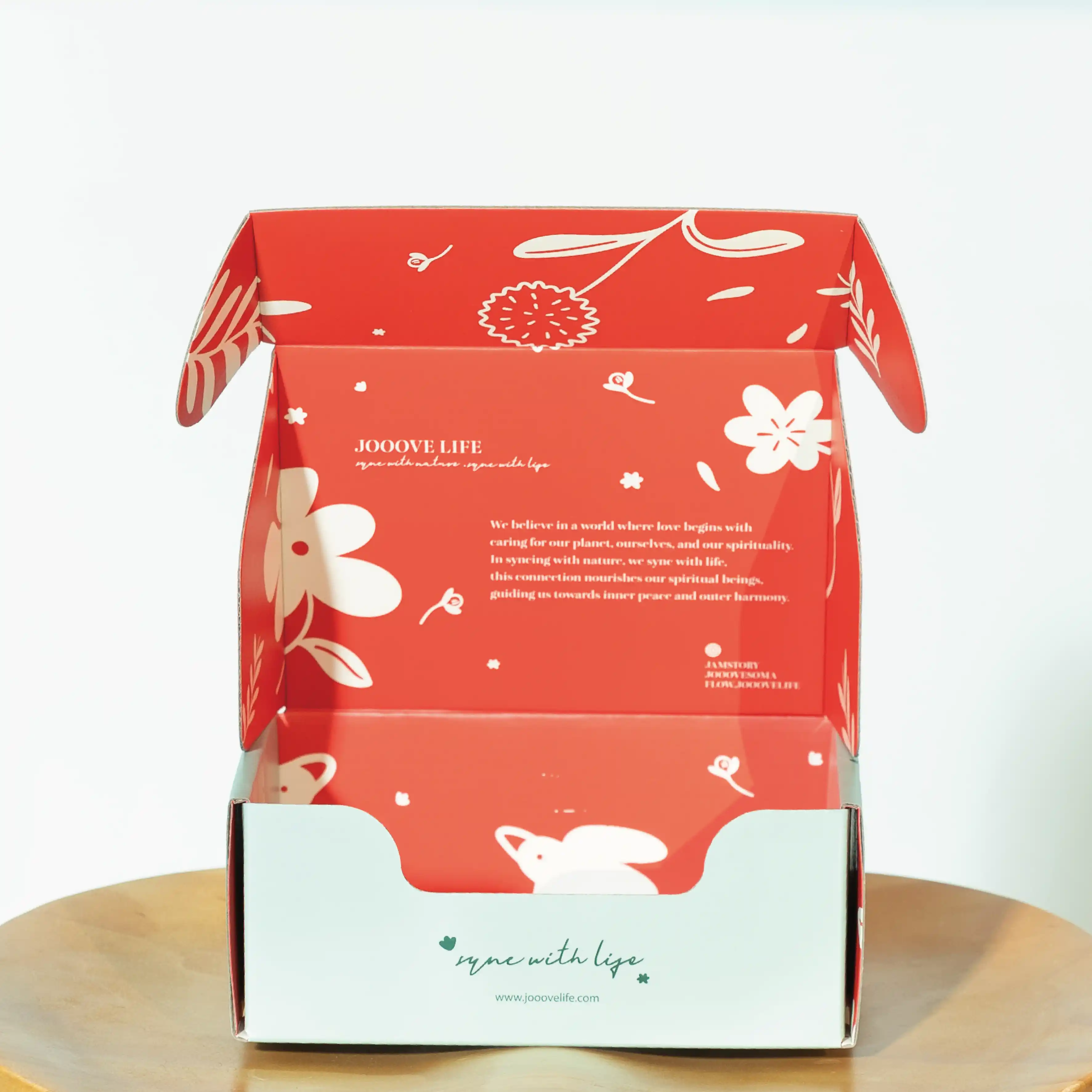 This is an open matte white cardboard box in a bright red colour with the brand's "JOOOVE LIFE" printed on the box. The box is also printed with a white flower and leaf pattern and a message about the brand's philosophy.