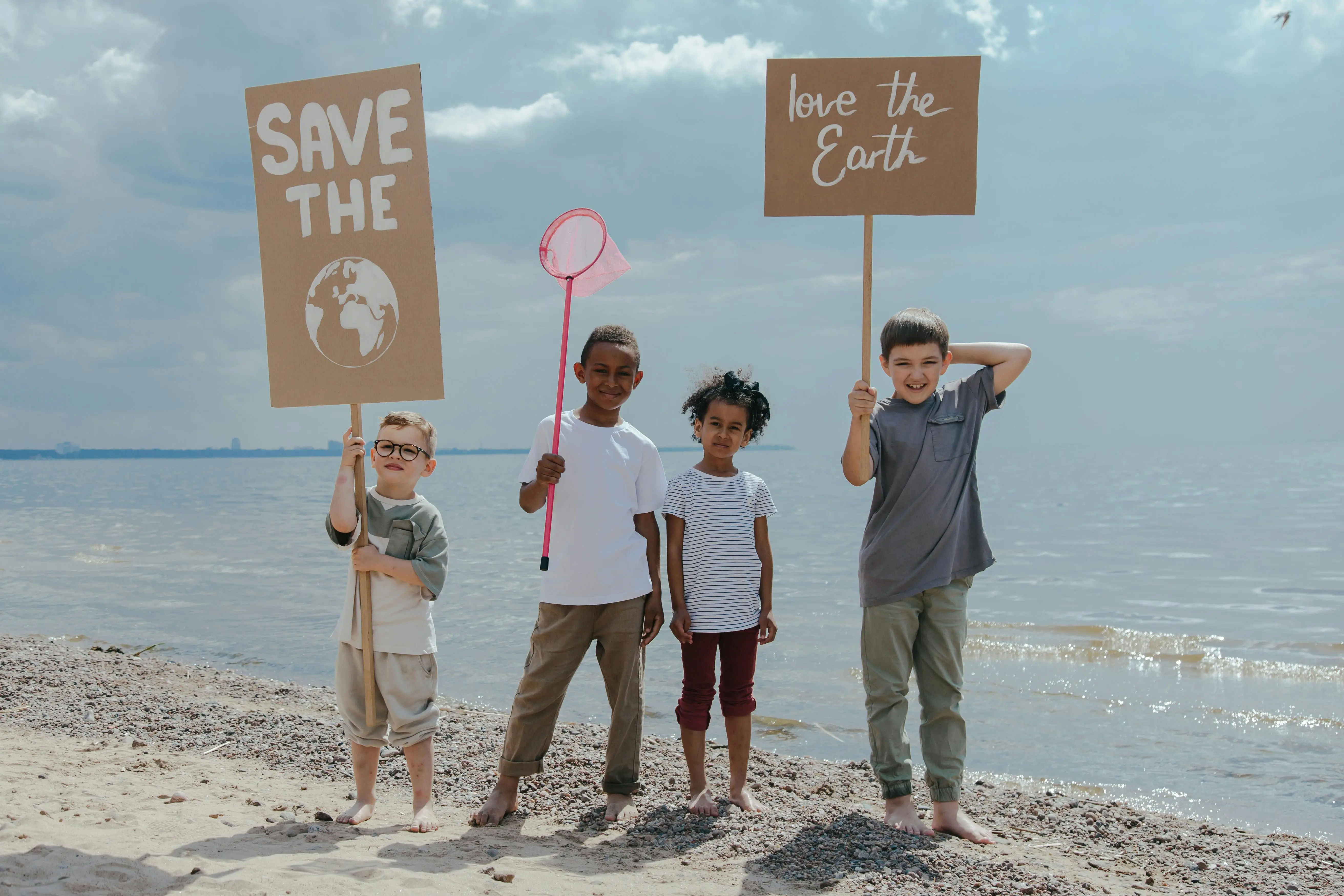 The picture shows four children holding up a sign that says “save the earth, love the earth”